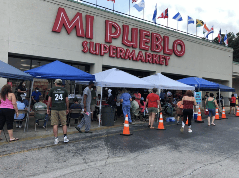 The exterior of Mi Pueblo Supermarket, when the Alabama Coalition for Immigrant Justice is hosting a free COVID vaccine equity event, with several tents and stations full of volunteers and nurses, and the general public.