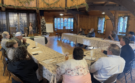 ACLC Black Lung Organizer, Courtney Rhoades Mullins, leads an overview of finding self-interest in organizing for a Black Lung Association Winter Organizing Training. People are sitting at tables, placed in a u-shape, with Courtney in the middle.